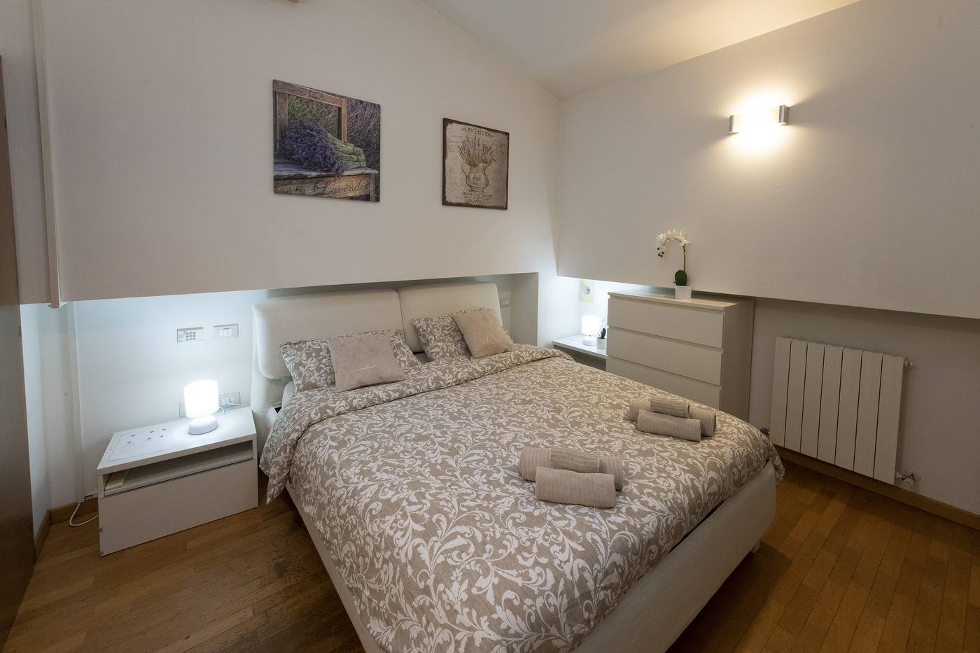 Lavander Room con letto matrimoniale, copriletto beige e quadri lavanda